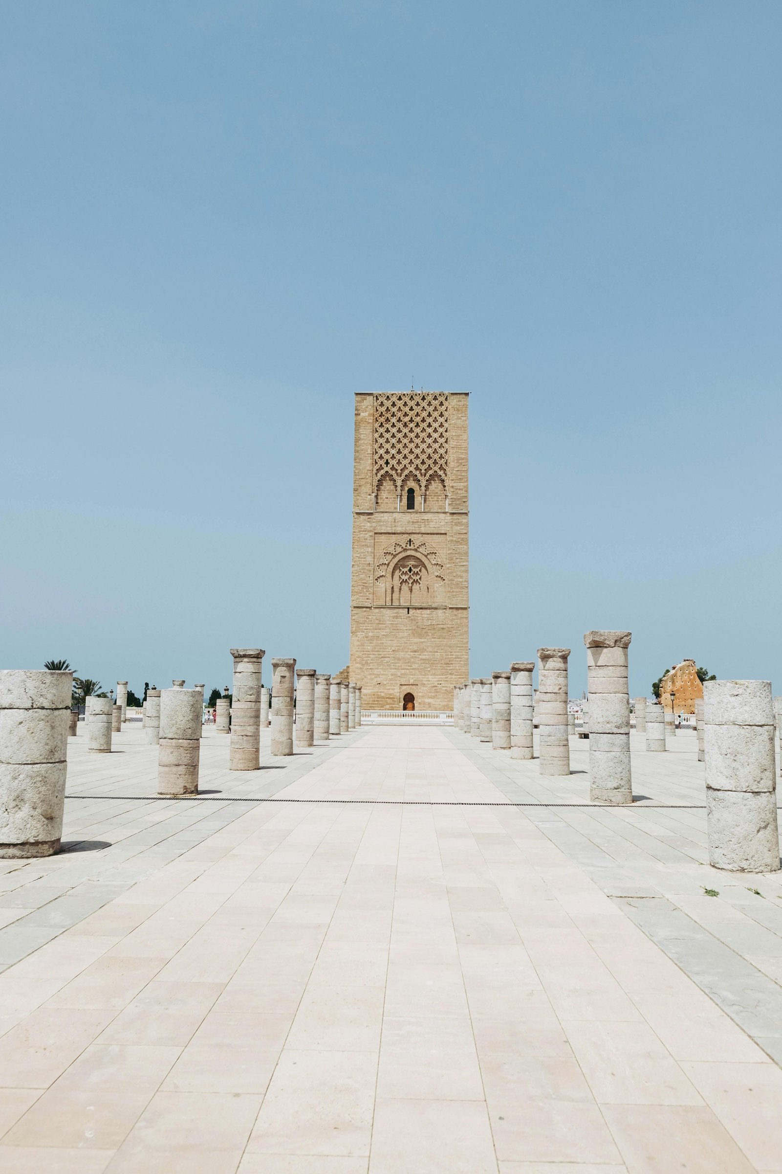 Hassan Tower in Rabat, Morocco stands tall amidst ancient columns under a clear blue sky.