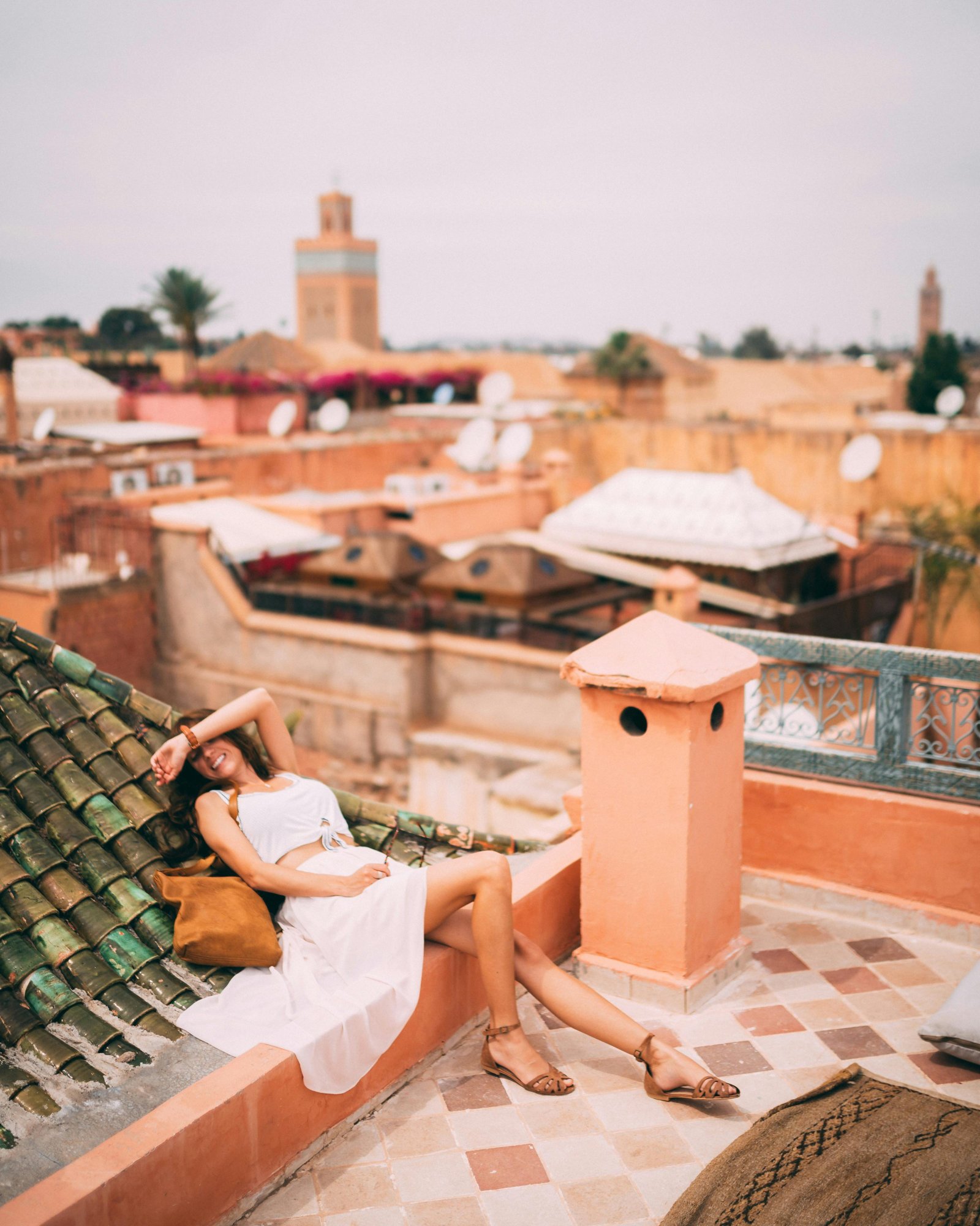Woman relaxing on a rooftop in Marrakesh, Morocco, capturing the vibrant urban skyline and warm tones of the city.