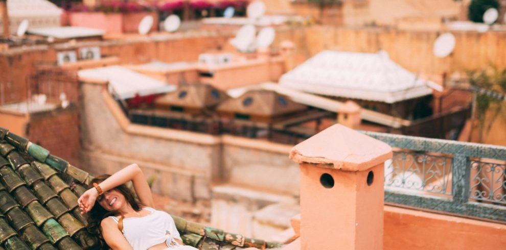 Woman relaxing on a rooftop in Marrakesh, Morocco, capturing the vibrant urban skyline and warm tones of the city.